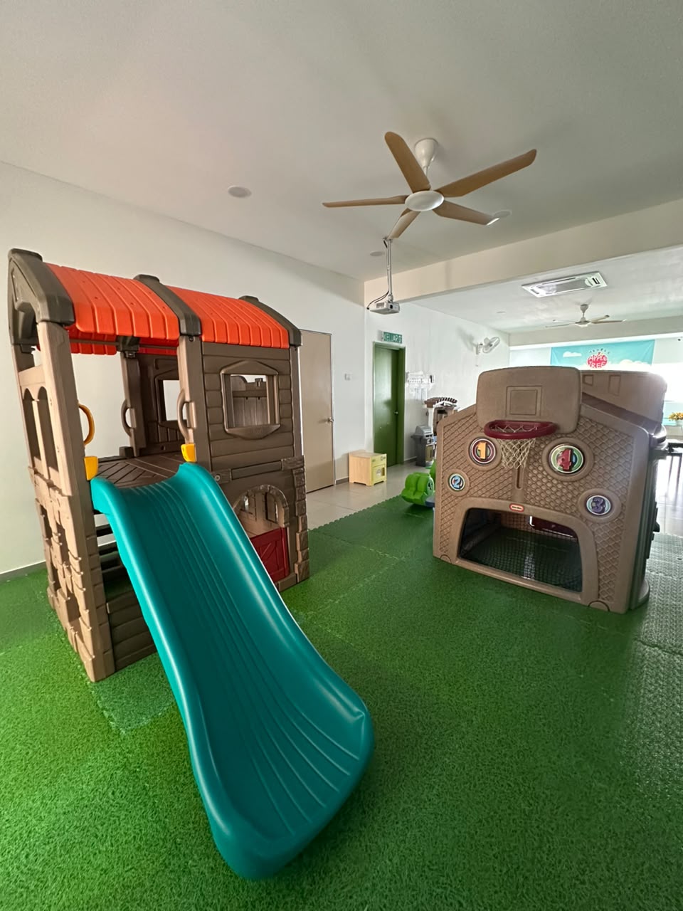 Indoor playhouse with slide and basketball hoop on artificial turf
